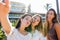 Three beautiful, funny playful girls have fun on vacation taking self portrait with smartphone making cheeky face . Carefree youth