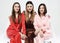 Three beautiful girlfriends dressed in pajamas sit on chairs and pose for the camera.