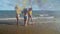 Three beautiful girls in bikinis dance happily on the beach with colored smoke fireworks using their hands to swing the colored sm