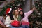 Three beautiful girls in santa hats smiles make selfies near of