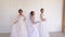 Three beautiful girls in wedding dresses pose for the photographer.