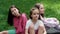 three beautiful happy tween teenagers girls in colorful clothes sitting on green grass in park. summertime. happy