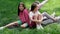 three beautiful happy tween teenagers girls in colorful clothes sitting on green grass in park. summertime. happy