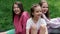 three beautiful happy tween teenagers girls in colorful clothes sitting on green grass in park. summertime. happy