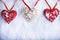 Three beautiful romantic vintage hearts are hanging on a red band on a white snow background. Love and St. Valentines Day concept