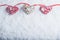 Three beautiful romantic vintage hearts are hanging on a red band on a white snow background. Love and St. Valentines Day concept.