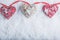 Three beautiful romantic vintage hearts are hanging on a red band on a white snow background. Love and St. Valentines Day concept.