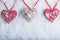 Three beautiful romantic vintage hearts are hanging on a red band on a white snow background. Love and St. Valentines Day concept.