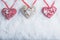 Three beautiful romantic vintage hearts are hanging on a red band on a white snow background. Love and St. Valentines Day concept.