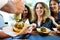 Three beautiful young women buying meatballs on a food truck.