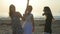 Three beautiful young women dancing on a beach at sunrise