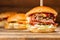 Three big burger with meat cooked on BBQ coal. Lunch on a wooden background. The concept of fast food and unhealthy food