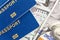 Three biometrical international passports over money background. Blue travel documents lying on US one hundred dollar banknotes. F