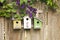 Three birdhouses on old wooden fence with flowers