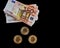 Three Bitcoin coins next to several 50 euro banknotes on a black background. Concept of economics, power, money, exchange,