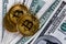 Three bitcoin shiners over us dollar banknotes close-up background