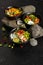 Three black ceramic bowls with assorted vegetarian Asian dishes of fish, shrimp, seafood, beans and avocado with yogurt dressing