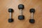 Three Black Dumbbells on Wooden Floor