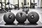 Three black filled weighted exercise balls in dense silicone cover with fluted surface inside Modern cross training Gym