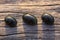 Three black jade translucent gemstones on wood