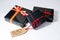 Three black wrapped gift boxes with a red cord and a Black Friday sales tag on a cardboard