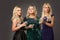 Three blonde girls wearing evening dresses driknking martini