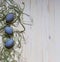Three blue easter eggs in green shavings on a light background