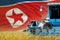 three blue modern combine harvesters with North Korea flag on rural field - close view, farming concept - industrial 3D