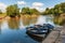 Three blue and white rowing boats moored on a tranquil river on a sunny day