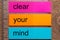 Three bookmark stickers with the word clear your mind on a dark natural wooden table