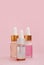 Three bottle of cosmetic oil, serum skin care products on a pink background. Place for text