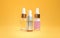 Three bottles of cosmetic oil, serum skin care products on an orange background. Place for text