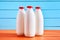 Three bottles of milk with red caps on orange wooden retro table