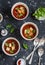 Three bowls of gazpacho soup on a dark background. Healthy vegetarian food.