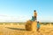 Three boys walk across the field with haystacks on a sunny day