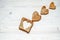 Three bread croutons in the form of hearts and a toast with Cutting inside heart lie on a wooden surface.
