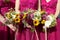 Three bridesmaids in lilac lace dresses with bouquets of fresh flowers, selective focus