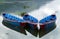 Three bright blue rowing boats on a lake with reflections.