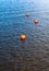 Three bright orange buoys floating on river water surface