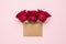 Three bright red rose flowers in brown craft envelope with copy space