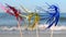 Three bright shiny colored cocktail decorations stand in sand near sea close-up.