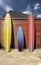 Three bright surfboards stand on the sand of the beach