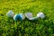 Three broken and damaged golf balls with one broken golf club lay on green grass. close up photo