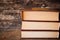 Three brown books in a stack vertically on a wooden