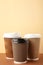 Three brown cups of coffee on beige background. Vertical foto