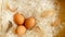 Three brown hen eggs and chicken feather on white shredded paper in wooden basket, top view photo