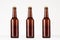 Three brown longneck beer bottle 330ml mock up. Template on white wood table.