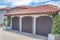 Three brown side-hinged garage doors and two concrete planters with vines