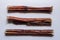 Three bully sticks. Dried bull pizzle regular for pets. White background. Shooting from above. Macro.