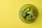 Three bunches of broccoli in dark round glass plate lies on scratched yellow concrete desk on kitchen